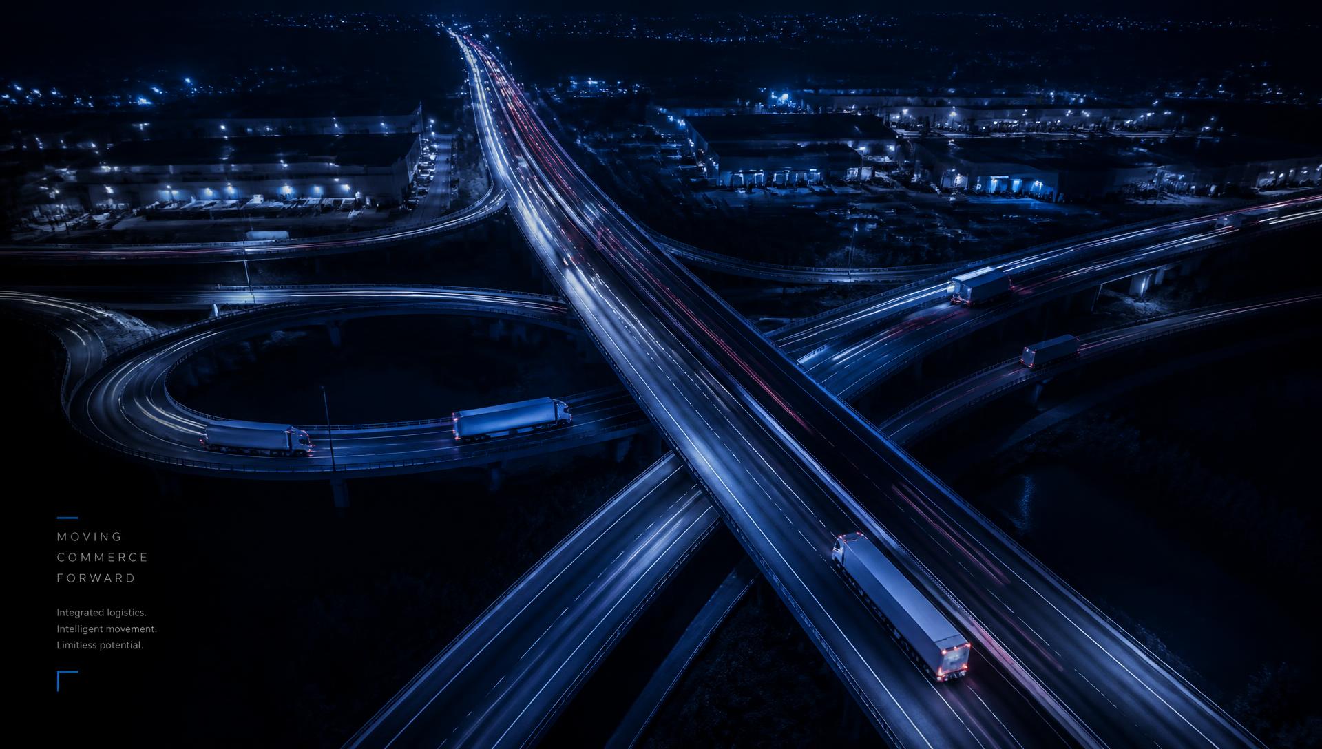 Aerial night view of a freight highway interchange with light trails